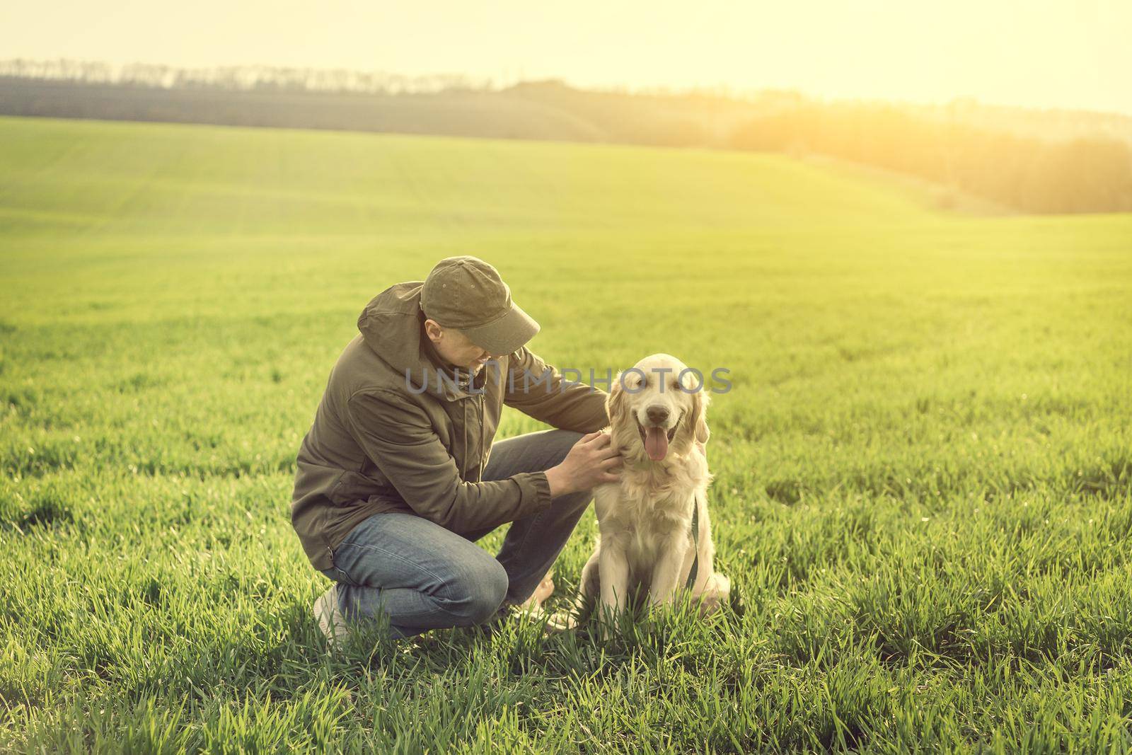 Cute dog with handsome man on green field in spring