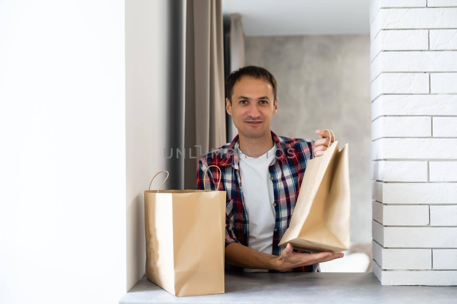 delivery, mail and people concept - happy man delivering food in disposable paper bag to customer home