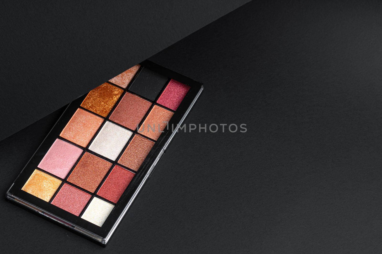 Color professional cosmetic palette on a dark background, close up