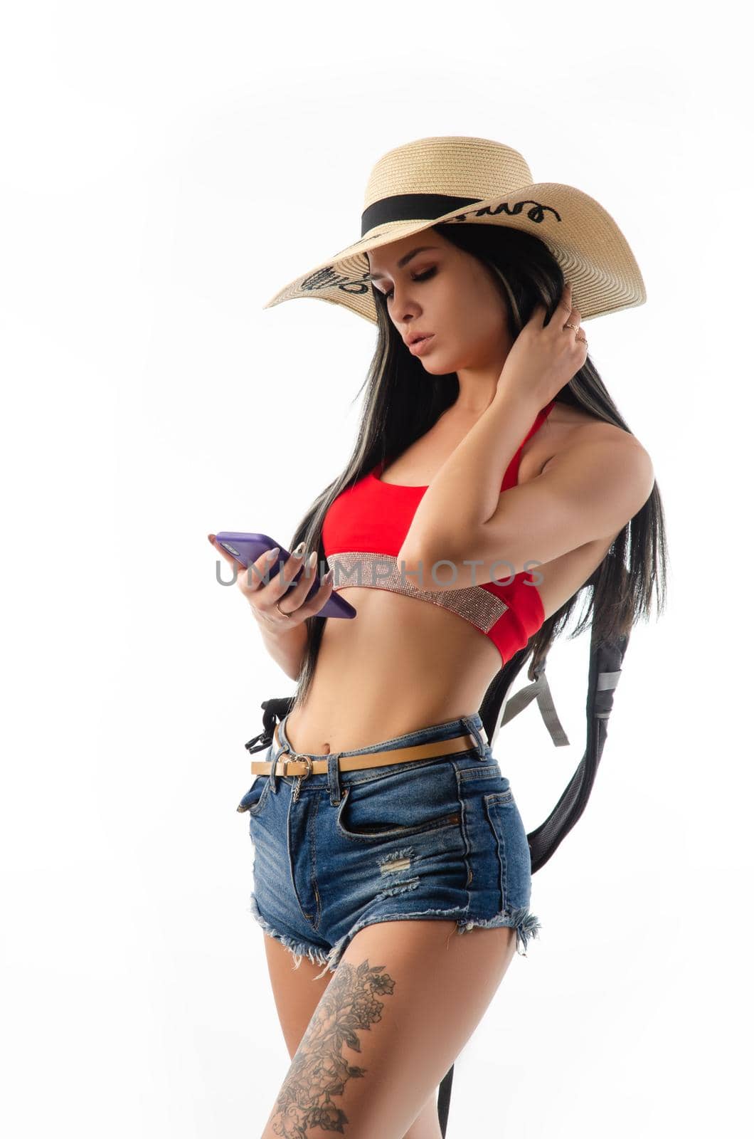 the brunette in a hat in summer clothes slim and sexy with a phone isolated on a white background