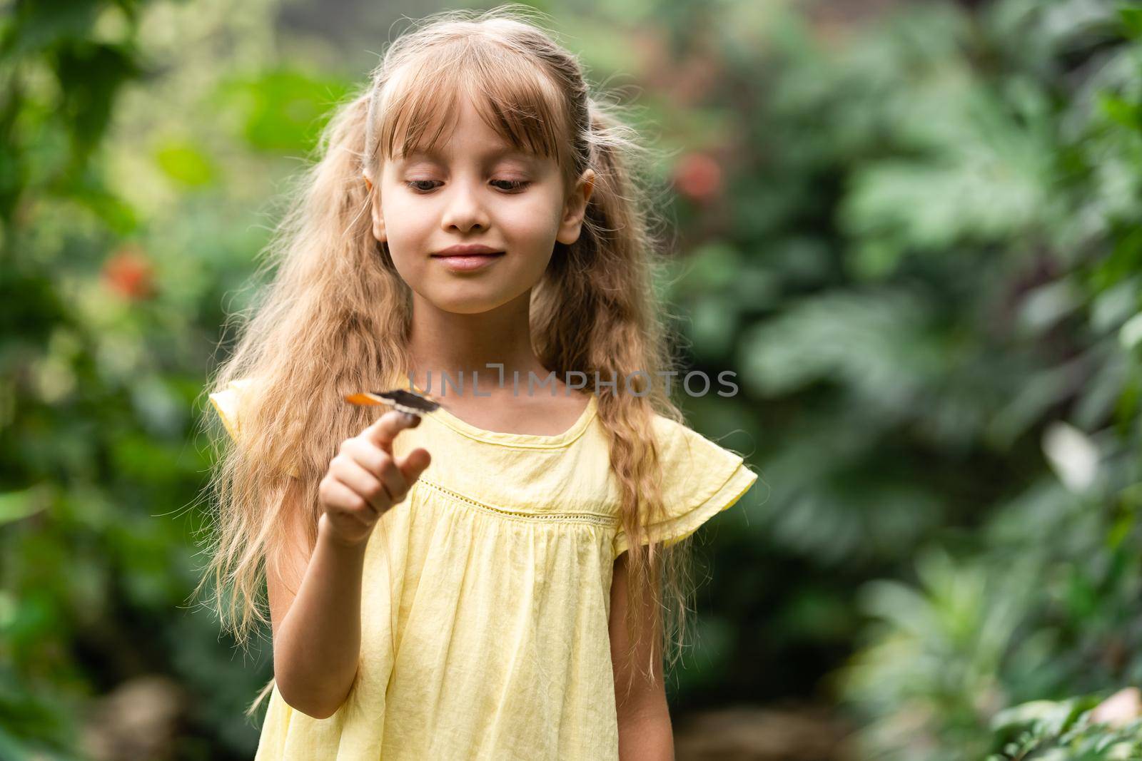 cute little girl holding living beautiful butterfly on her hand