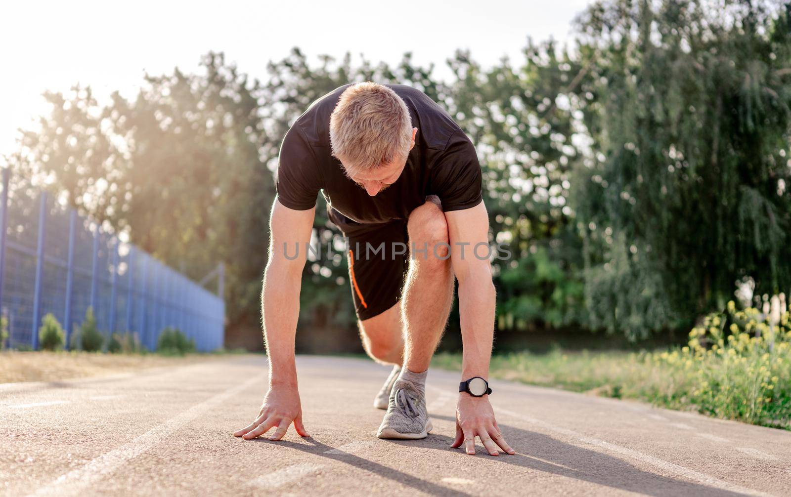 Man guy going to start running at the stadium and standing in the pose outdoors. Male person during workout. Sportsman exercising