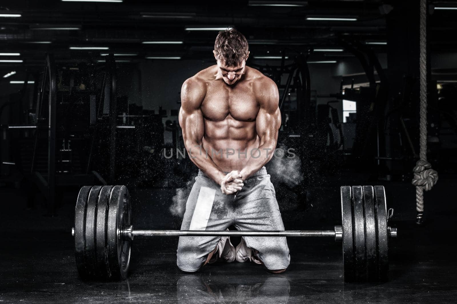 Athletic shirtless young sports man - fitness model with barbell in gym.