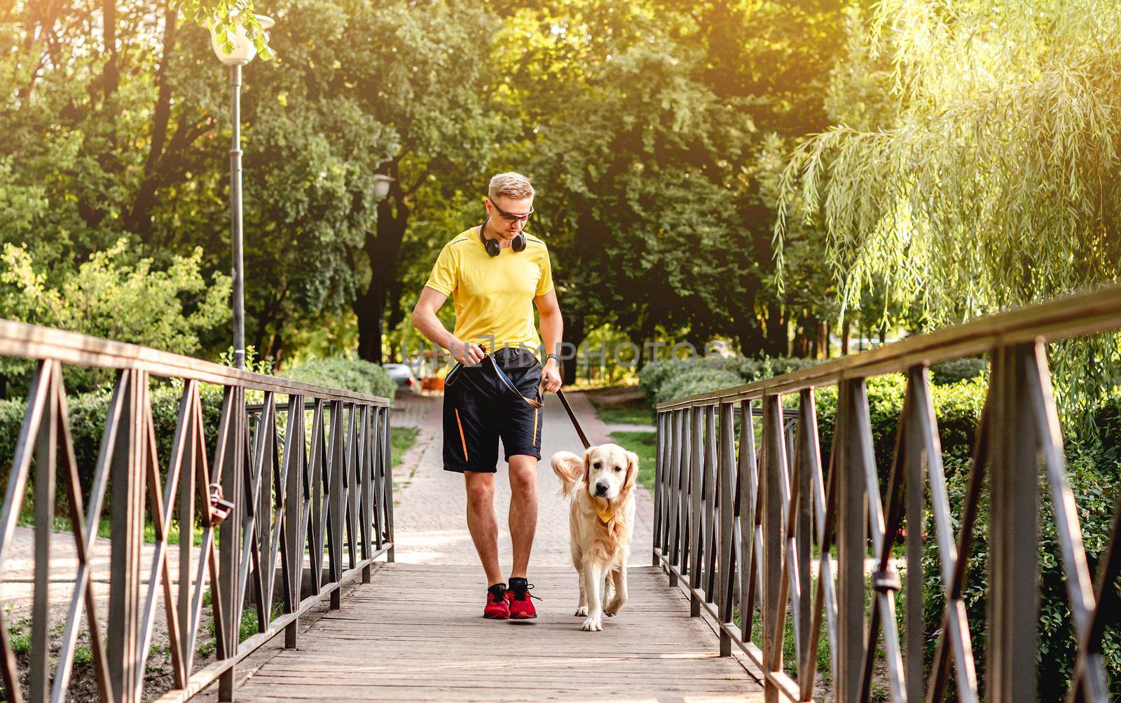 Young man jogging in park with golden retriever dog