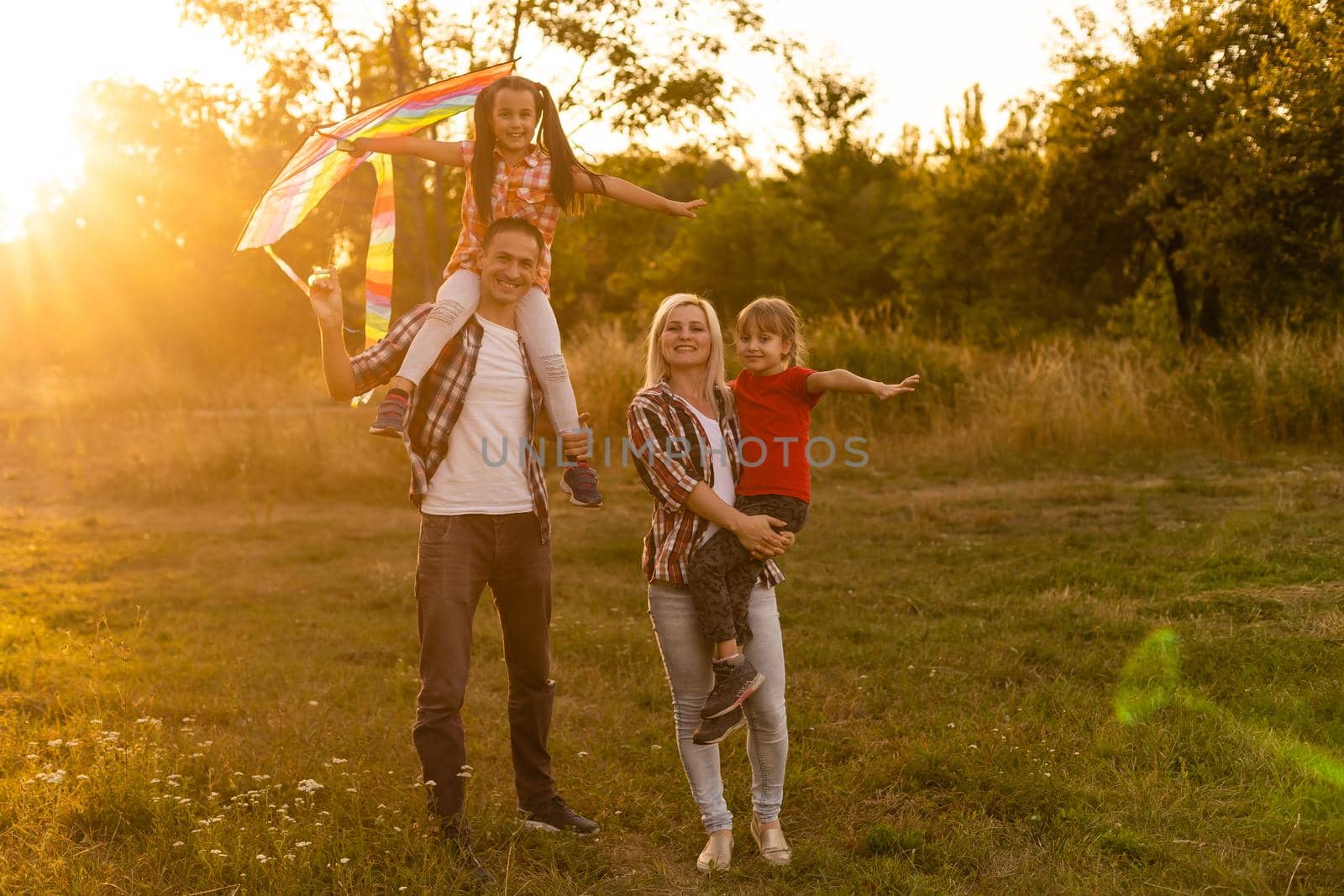 Happy family father of mother and daughters launch a kite on nature at sunset