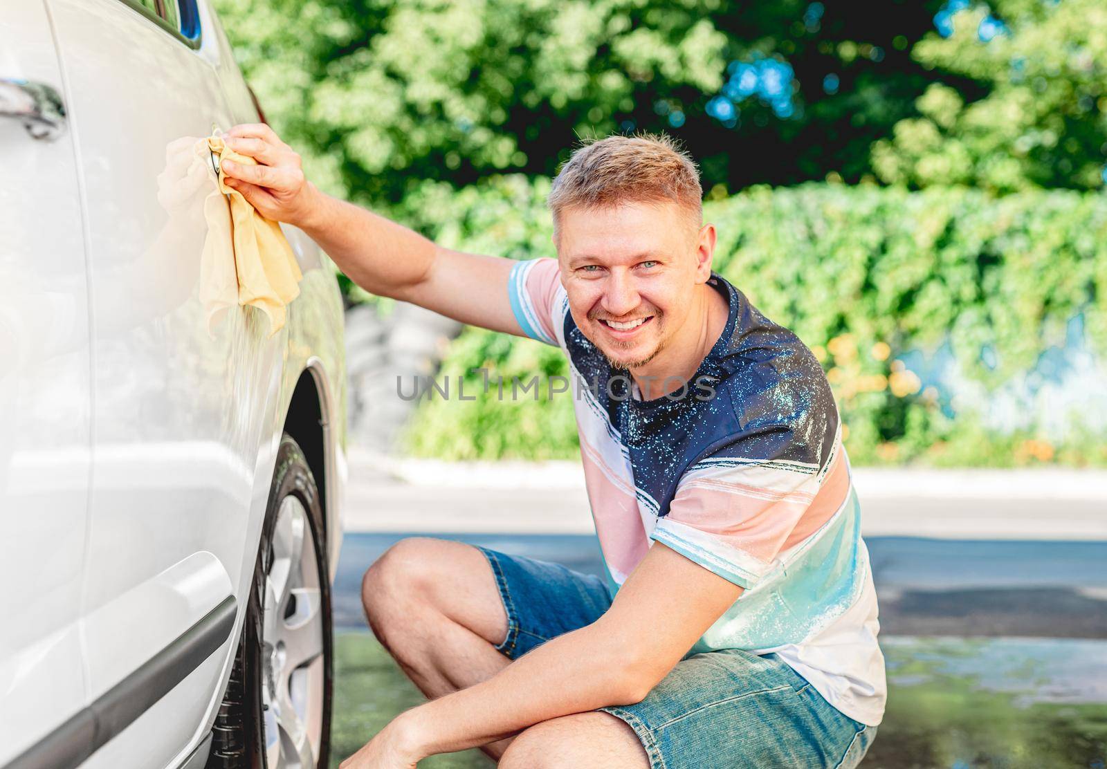 Man cleaning car handle with rag during car wash