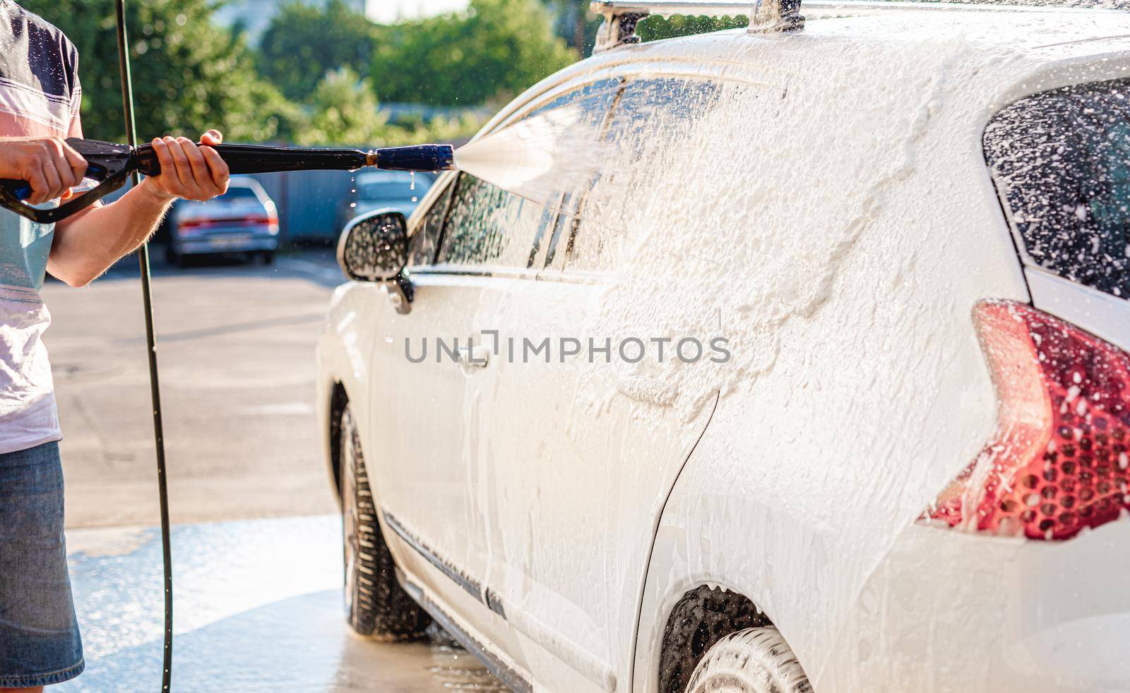 Applying washing foam on car at car wash station