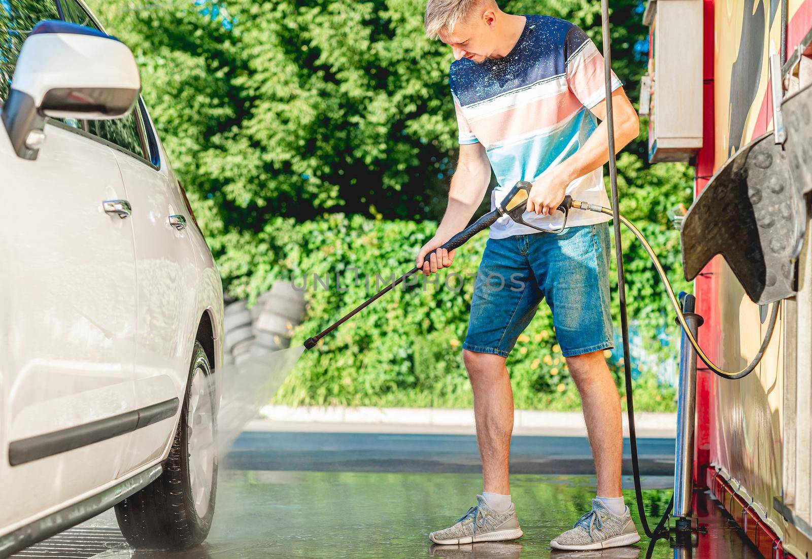 Man is washing car with high pressure water