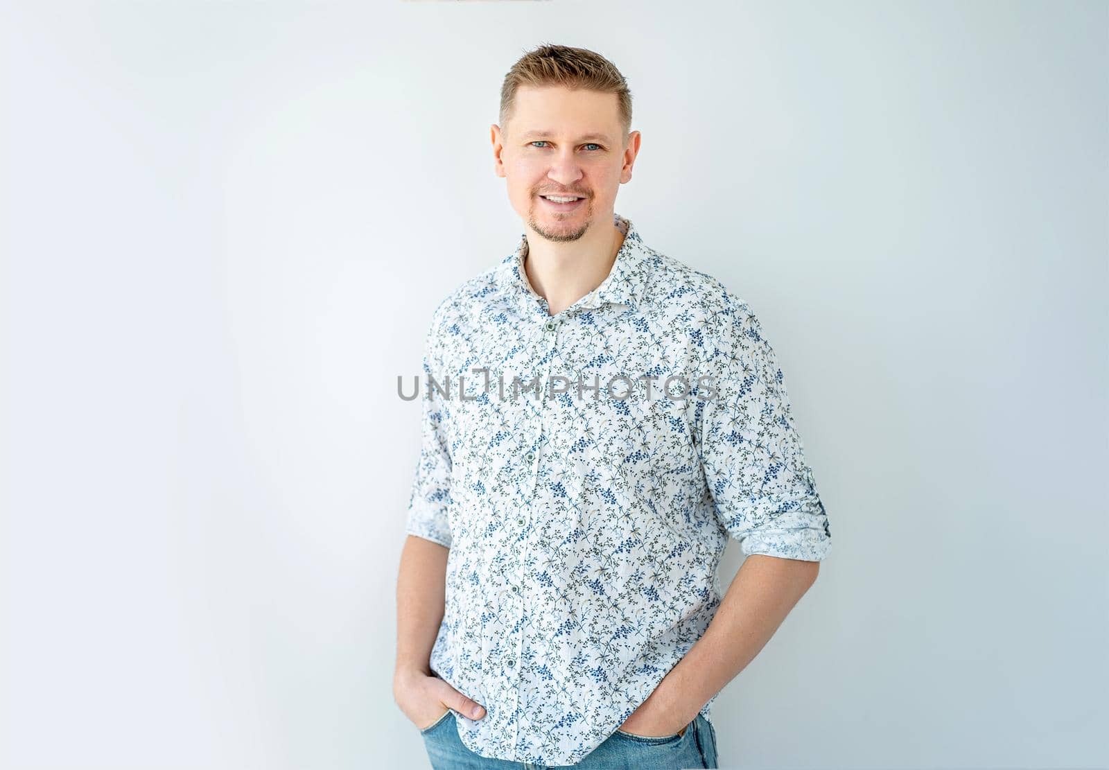 Smiling man posing with hands in pockets indoors