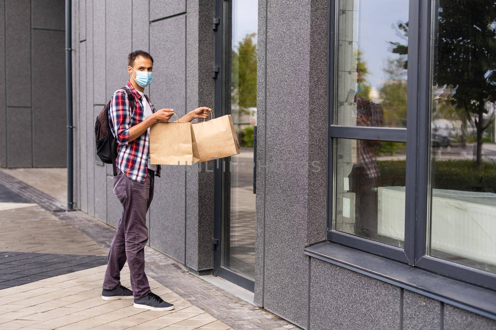 Delivery man holding paper bag with food, food delivery man in protective mask