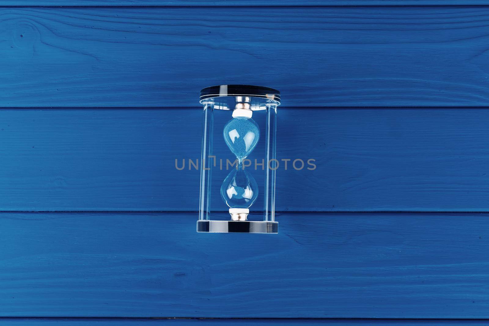 Top view of an hourglass flat lay on classic blue background. Close up.