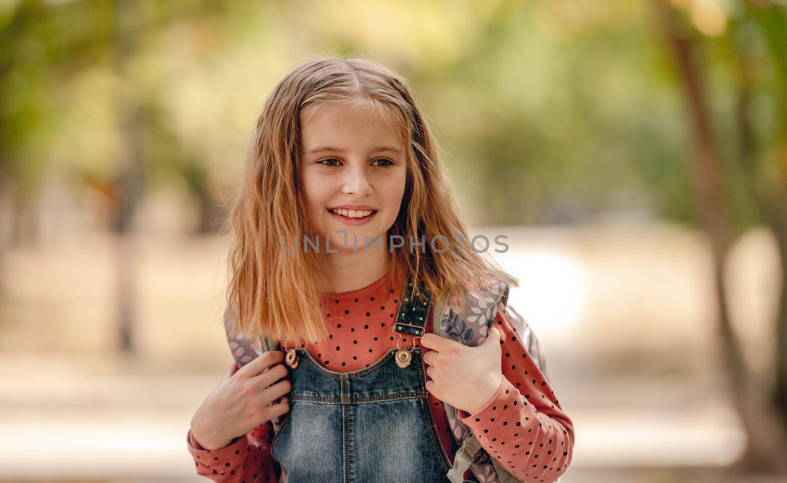 Preteen school girl with backpack closeup portrait outdoors. Pretty pupil female kid after education class in autumn park