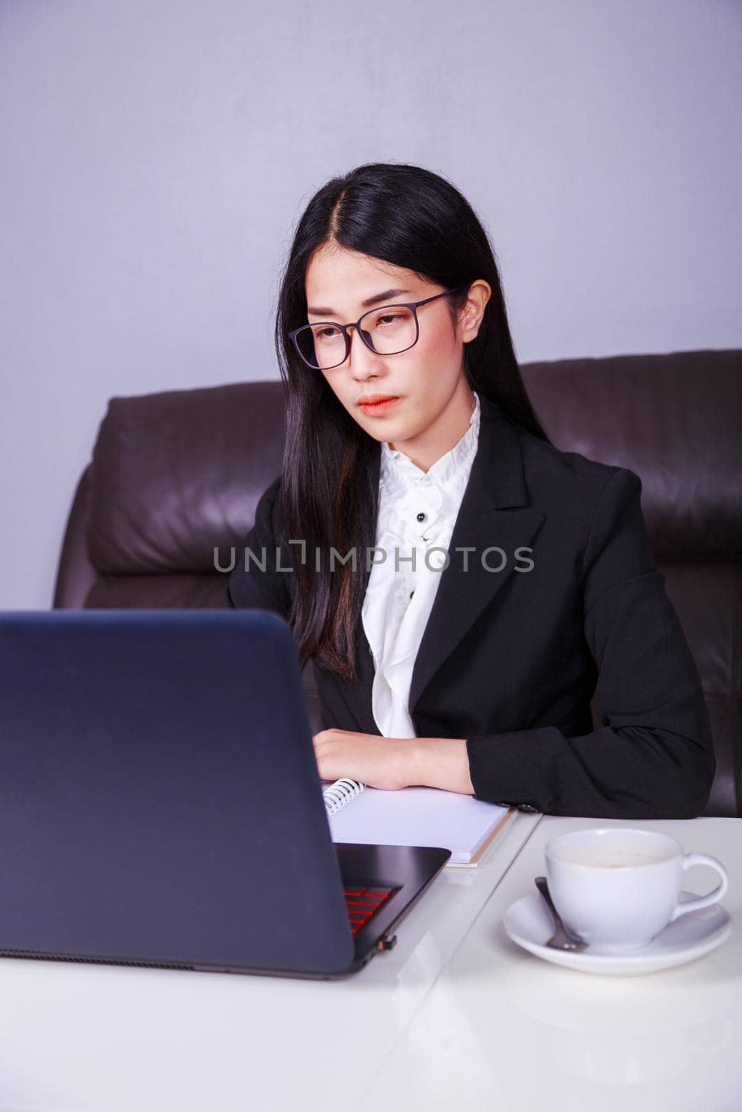 business woman sitting at the desk and using laptop computer for her work by geargodz