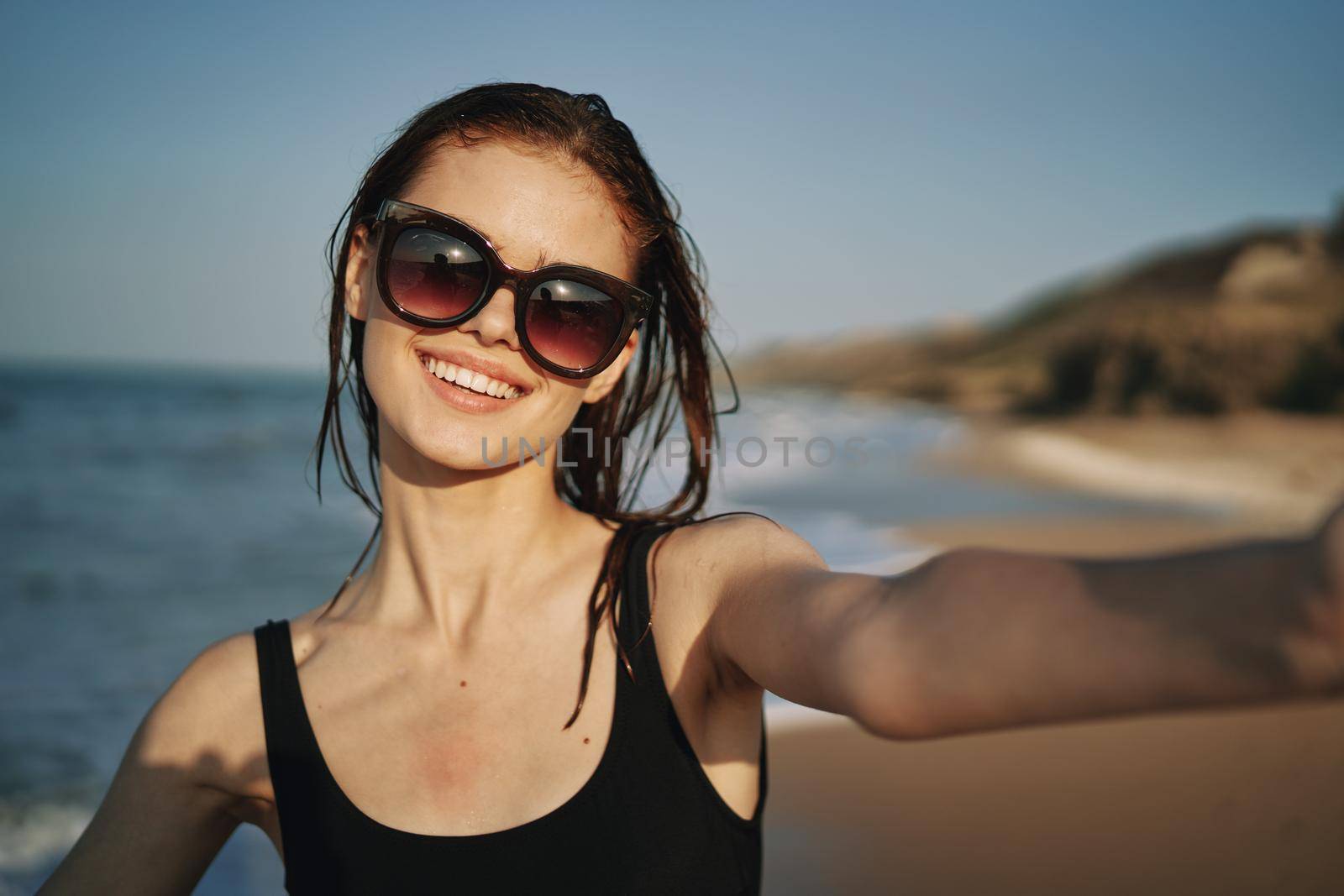 cheerful woman in a black swimsuit walking along the beach tropics summer. High quality photo