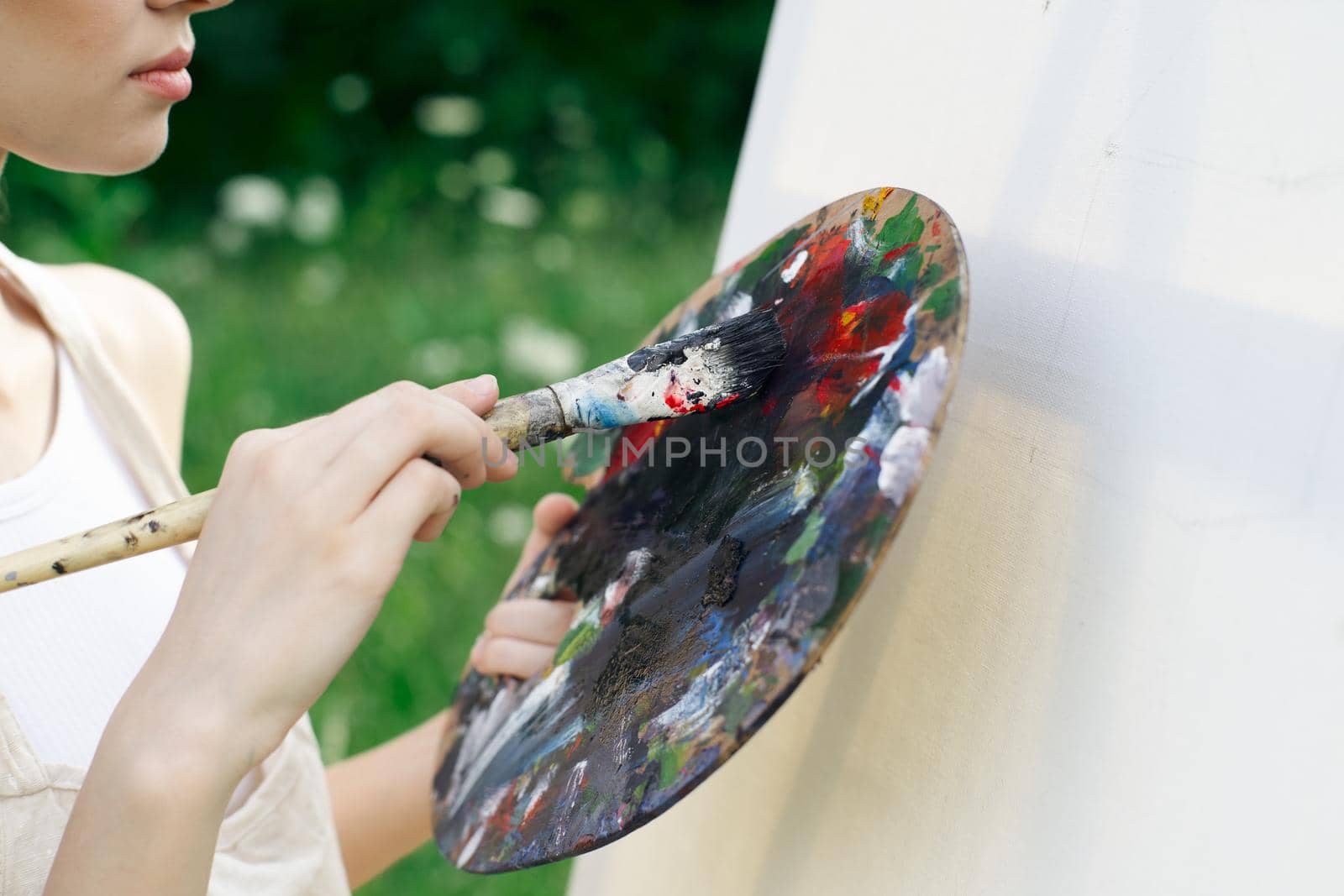 woman artist in white dress paint palette drawing close-up. High quality photo