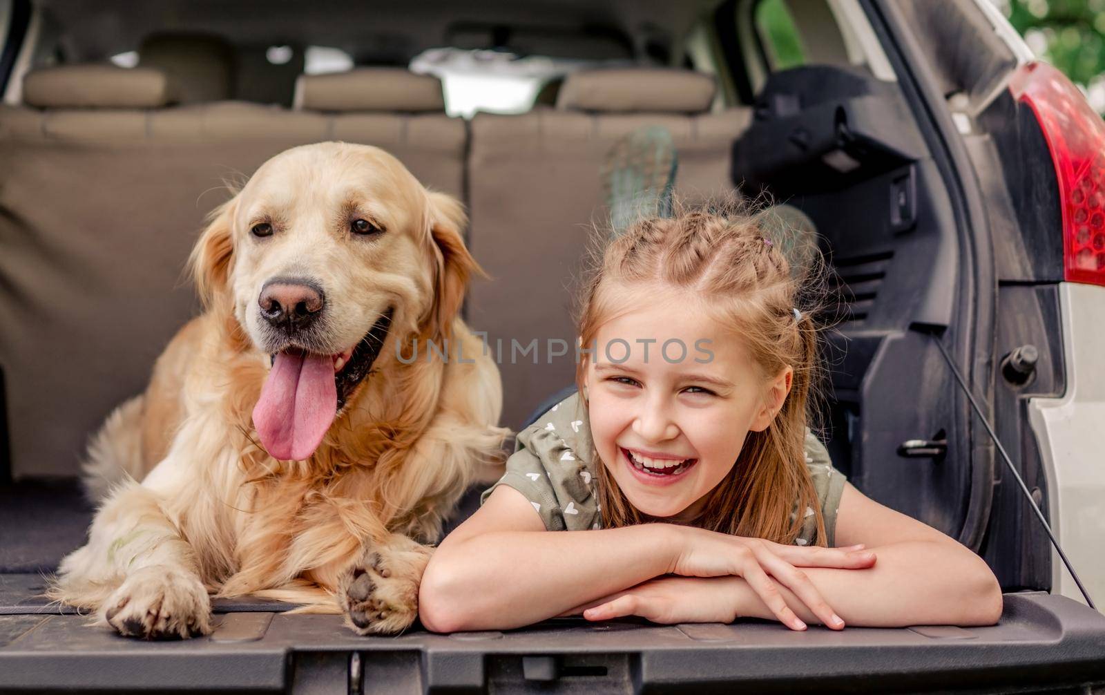 Preteen girl with golden retriever dog in the car by tan4ikk1