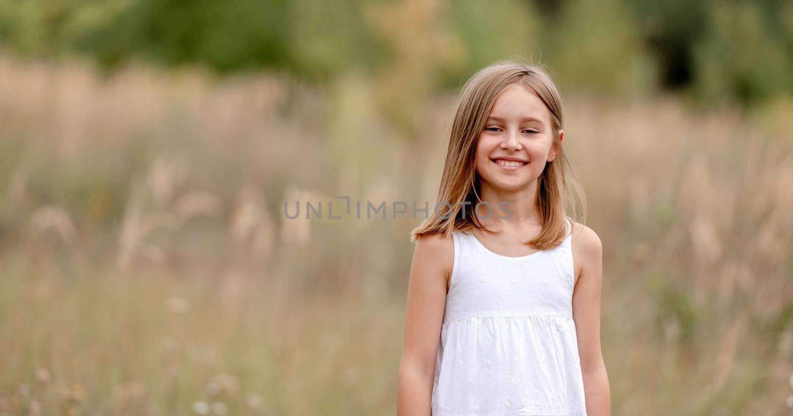 Preteen girl in the field smiling and looking at camera. Pretty child kid at the nature