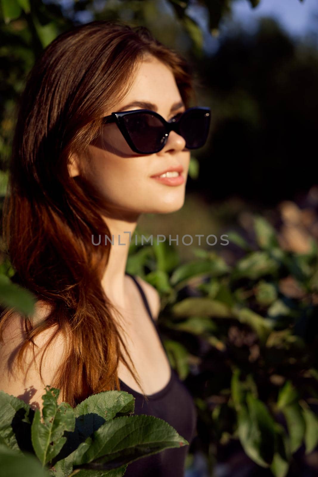 pretty woman in sunglasses in summer outdoors green leaves by Vichizh