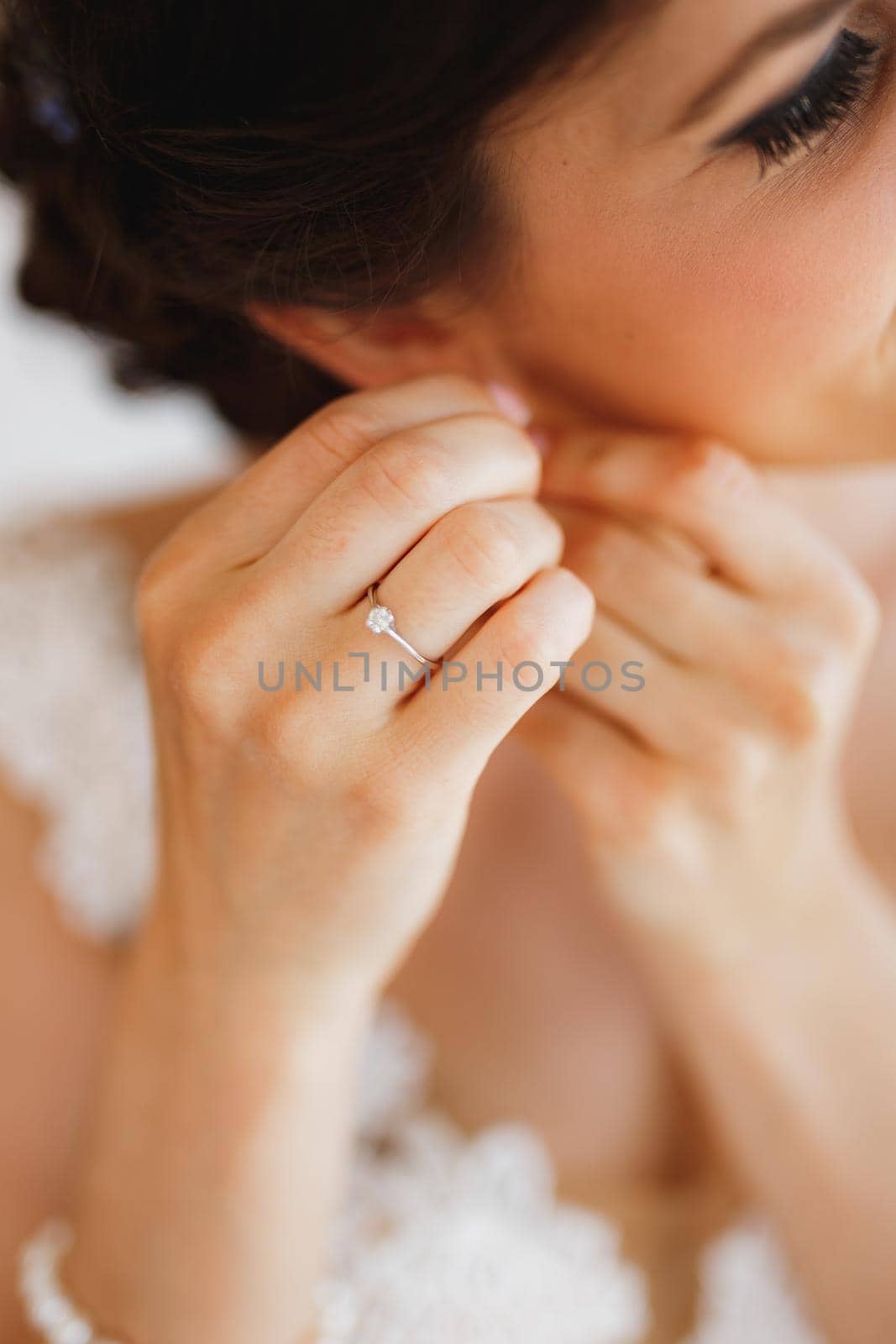 Bride in a white lace dress puts on an earring. Close-up. High quality photo
