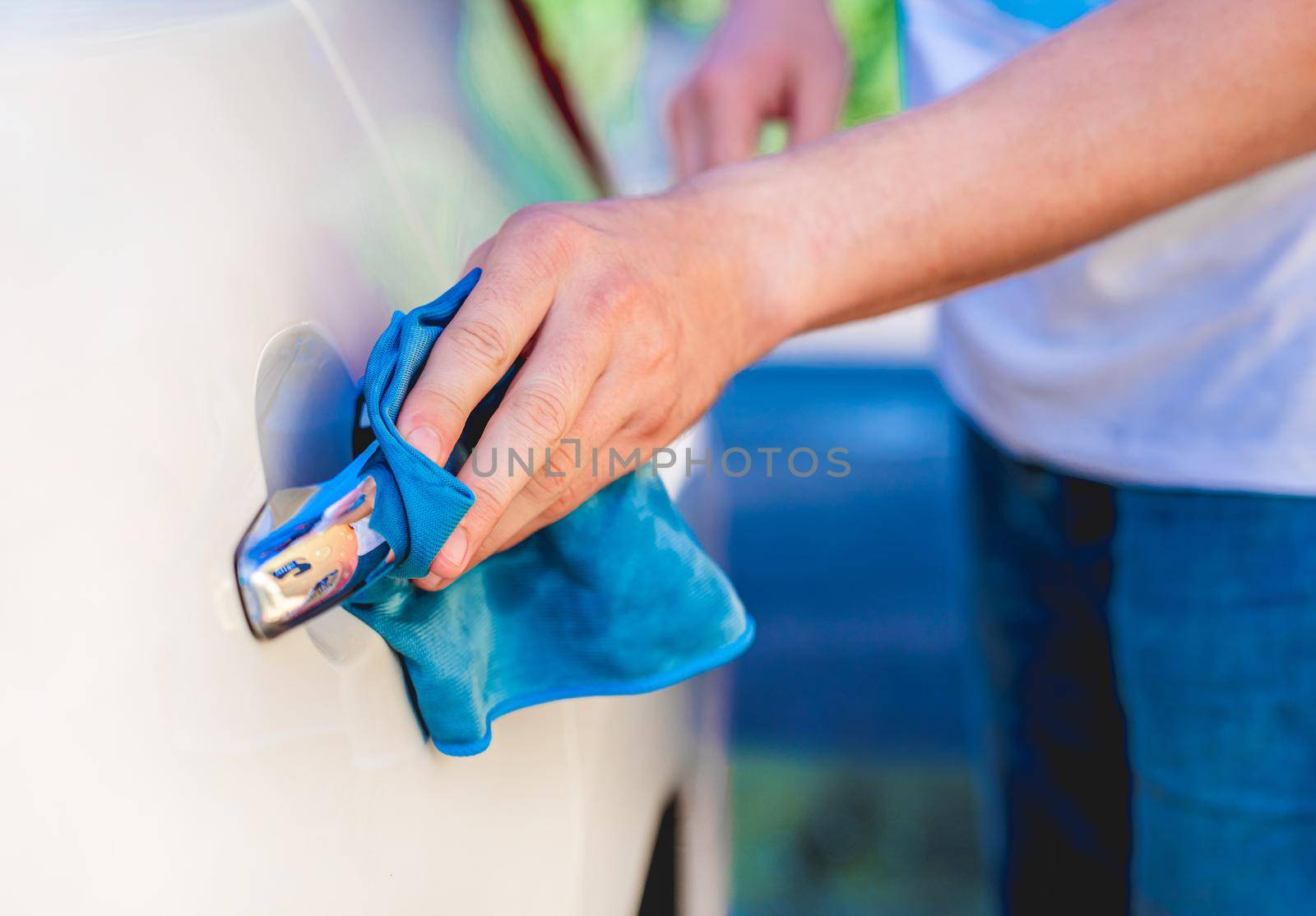 Hand with microfiber rag polishing car handle