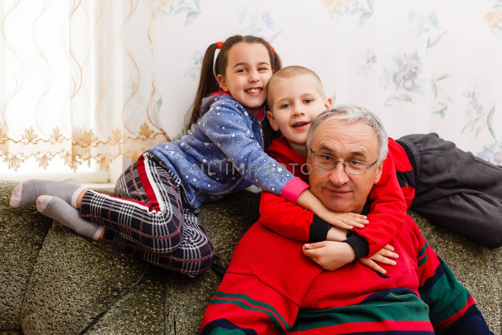 Grandparents spending time with grandchildren on couch by Andelov13