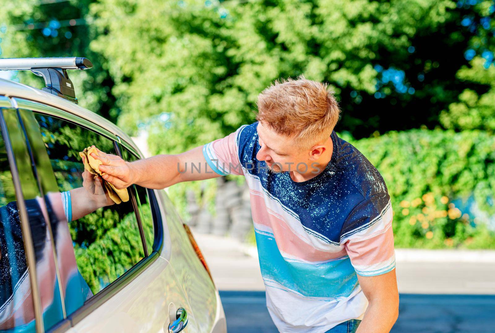 Man polishing shinning car window with cloth