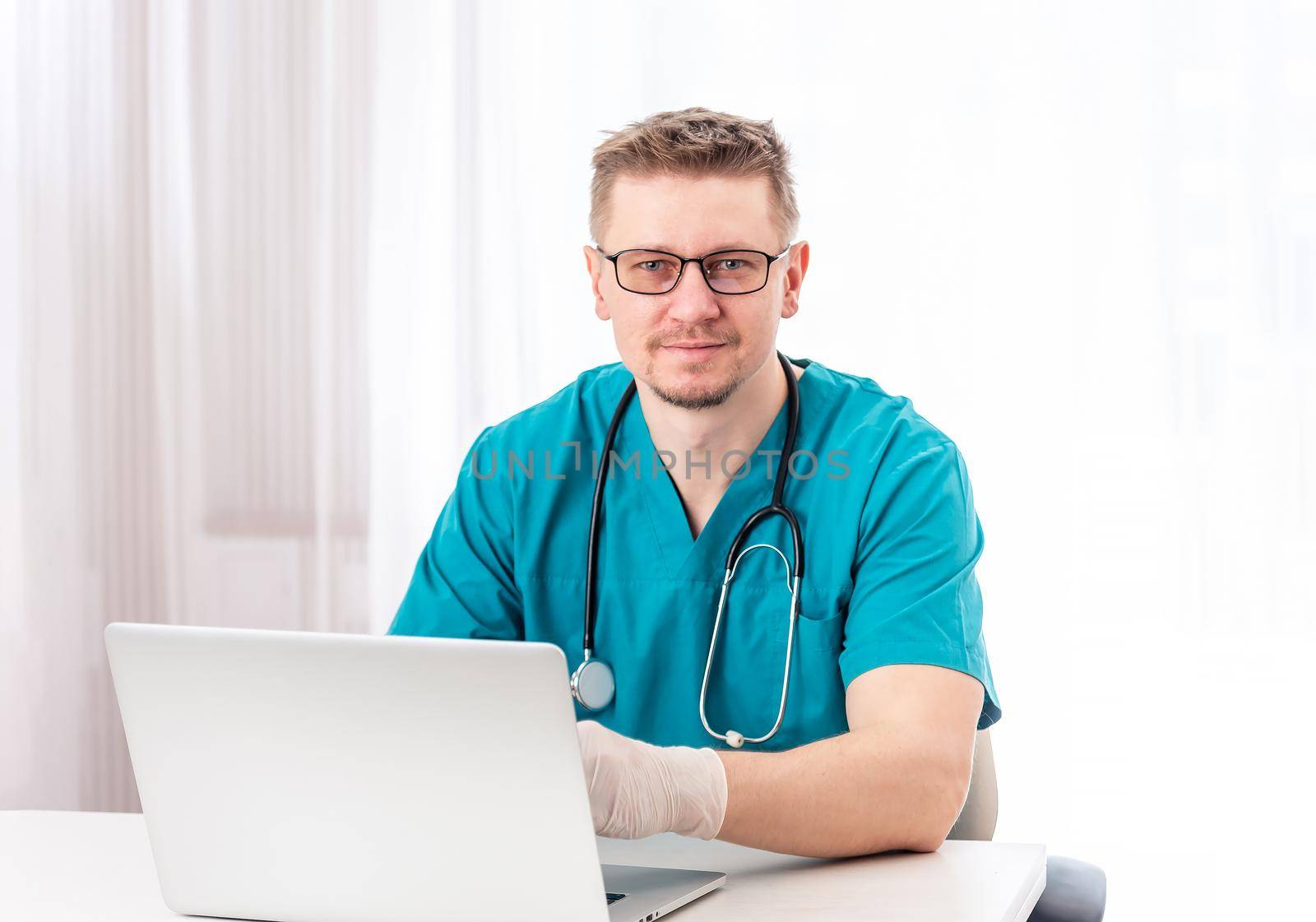 Handsome doctor sitting in reception cabinet, isolated on white