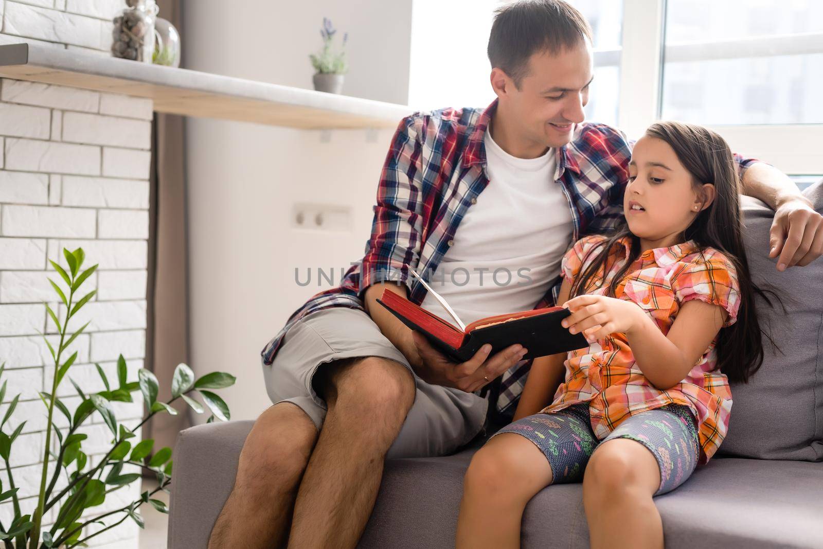 a young father with his little daughter reads the Bible