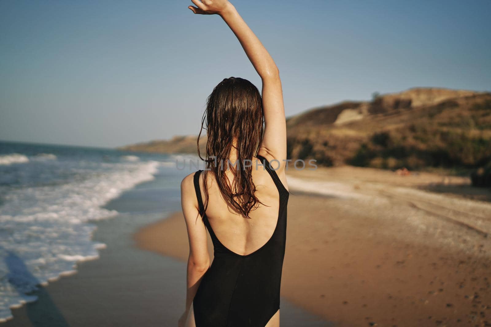 woman walks along the sandy shore in a black swimsuit sun tropics. High quality photo