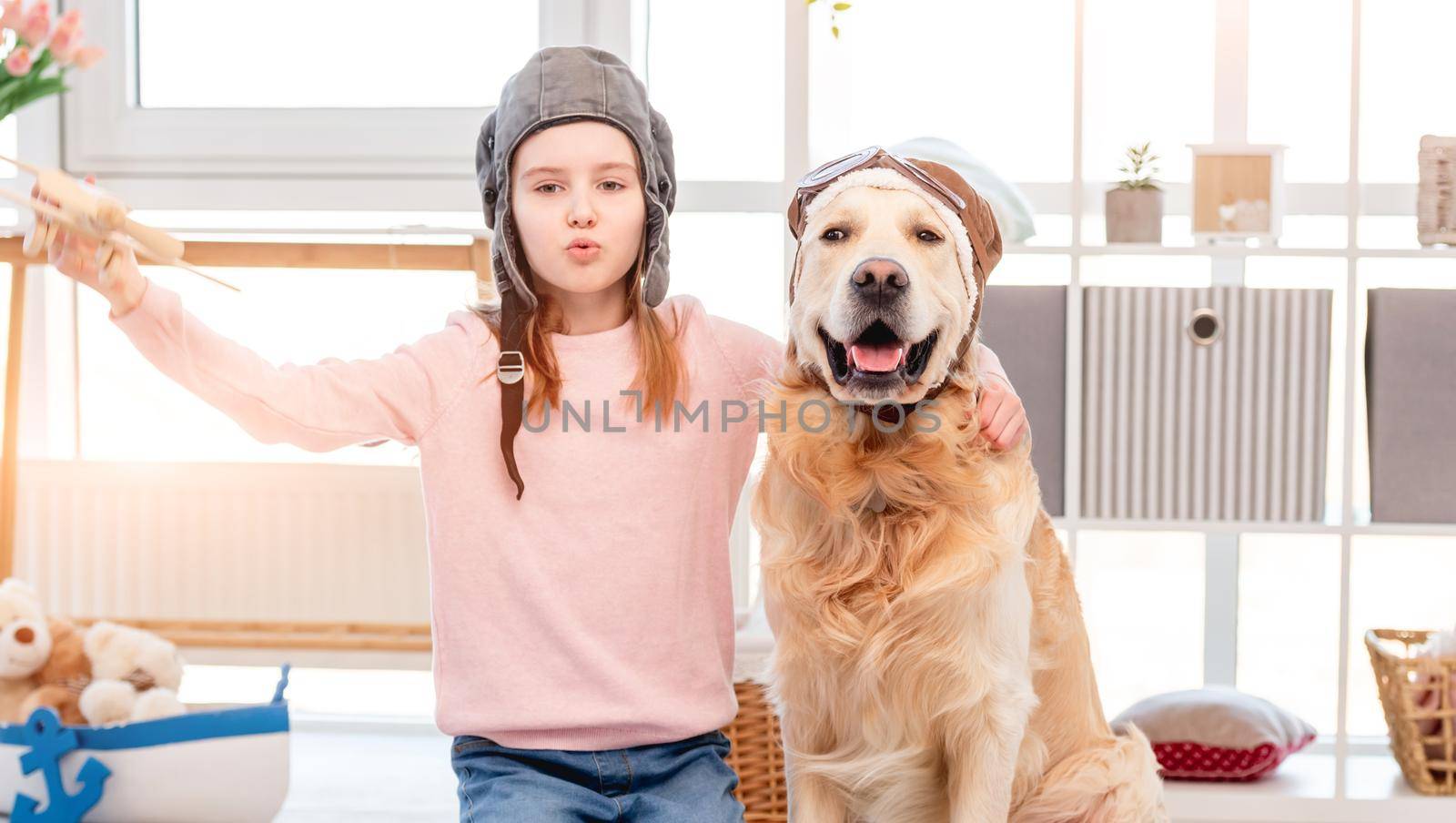 Little girl play in plane pilot with golden retriever dog by tan4ikk1