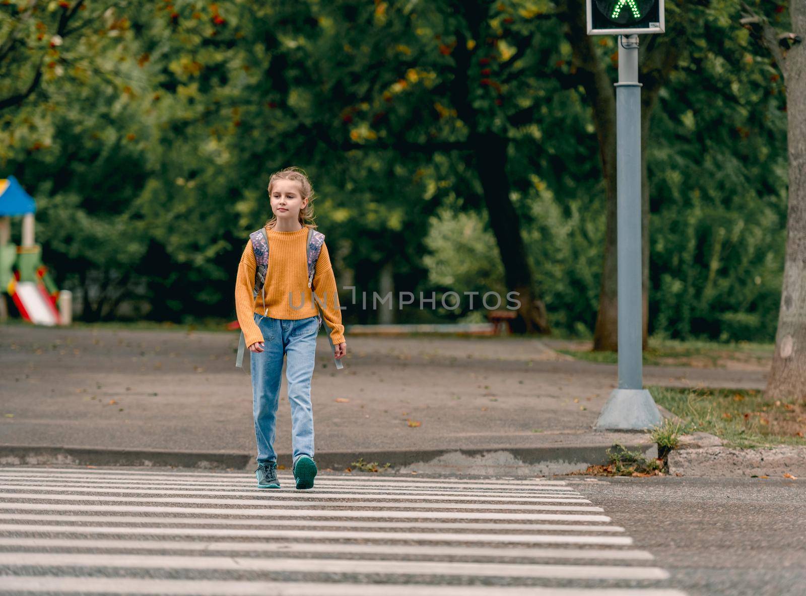 School girl with backpack outdoors walking. Pretty female child kid after lessons going home