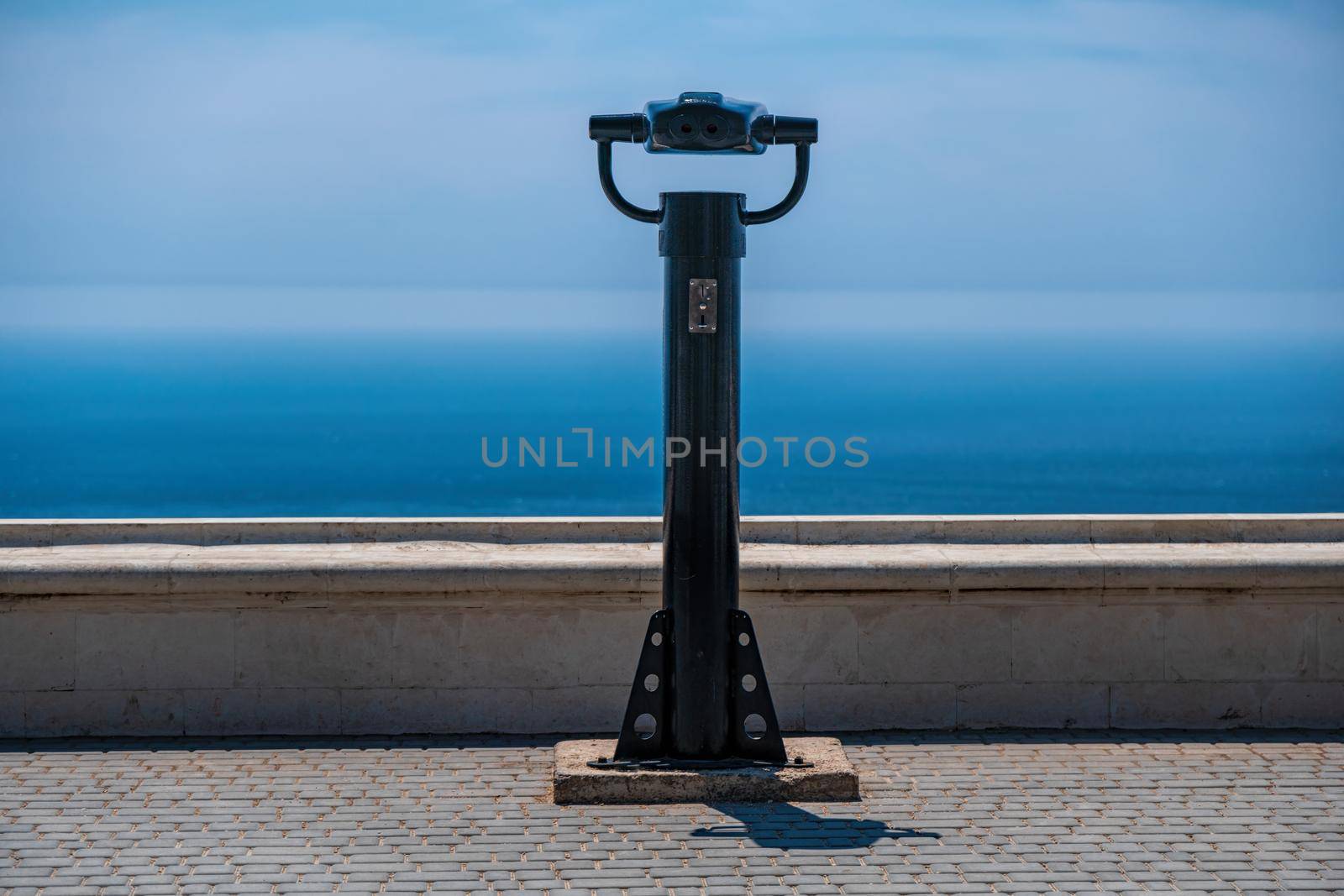 coin operated binoculars and blue sea background. Public panoramic binoculars to observe the sea view. Travel, relax or loneliness concept.