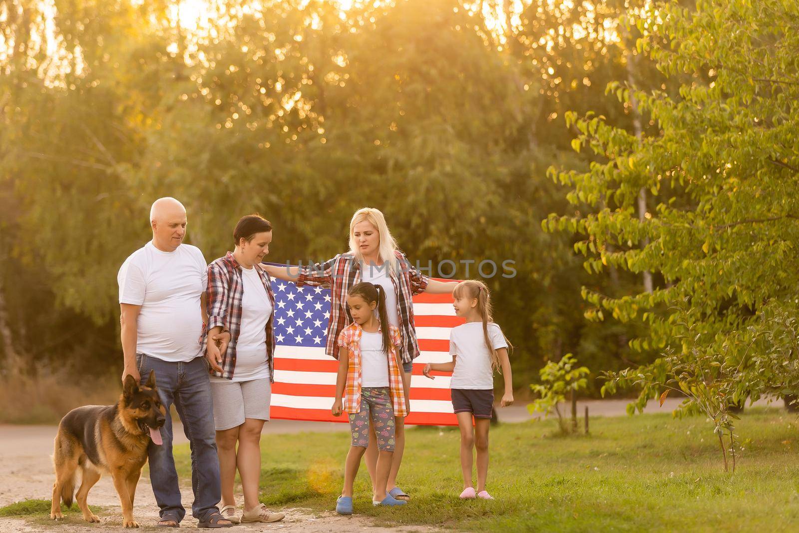 big family are walking walking american flags. Front view, american patriots on the park meadow. by Andelov13