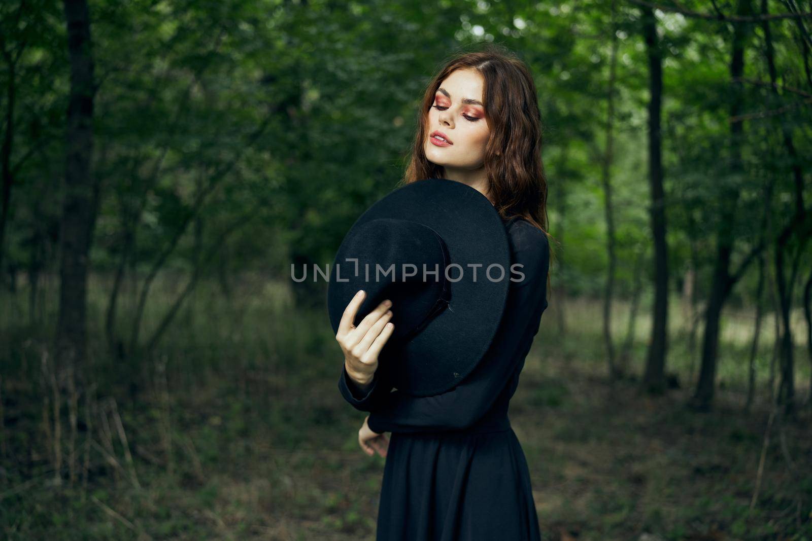 woman in the forest in a black hat gothic style Witch costume. High quality photo