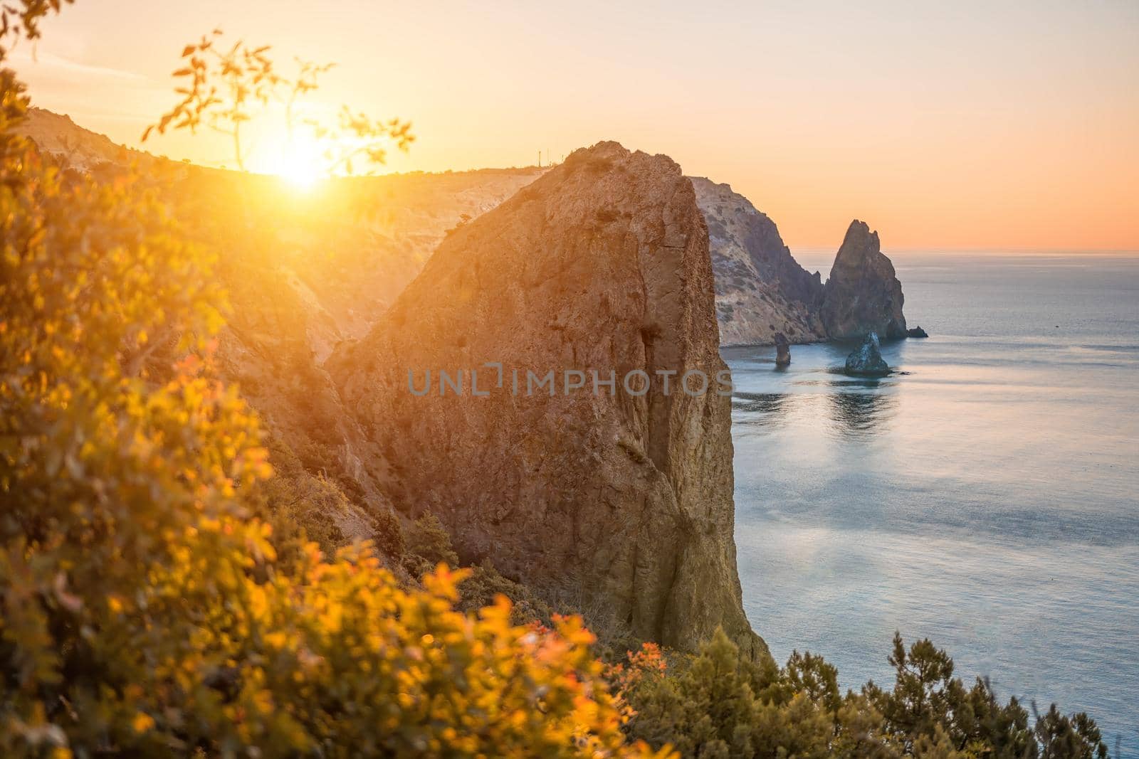 Autumn sea landscape with warm sunset light over rocky coastline. Calm sea on a background of rocky shores. The concept of perfect place for autumn travel and rest