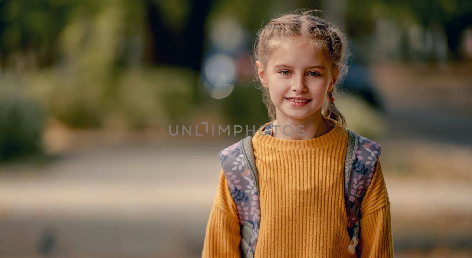 Preteen school girl with backpack looking at camera. Pretty pupil female kid portrait outdoors after education class in autumn park