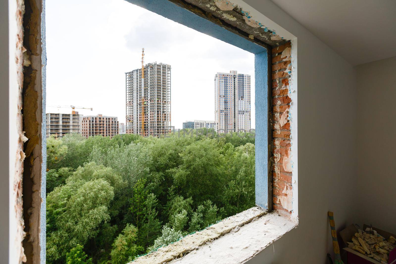 Empty frame on a wide panoramic window. Gorgeous view from the window of an apartment in a multi-storey building. Roofs of houses and trees from a height. Beautiful view through the window. Frame for