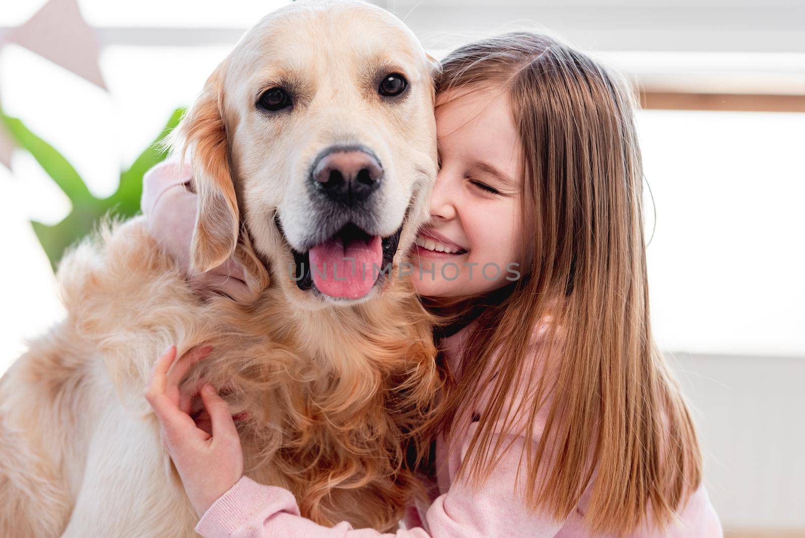 Little beautiful girl petting adorable golden retriever dog. Closeup portrait of child and doggy