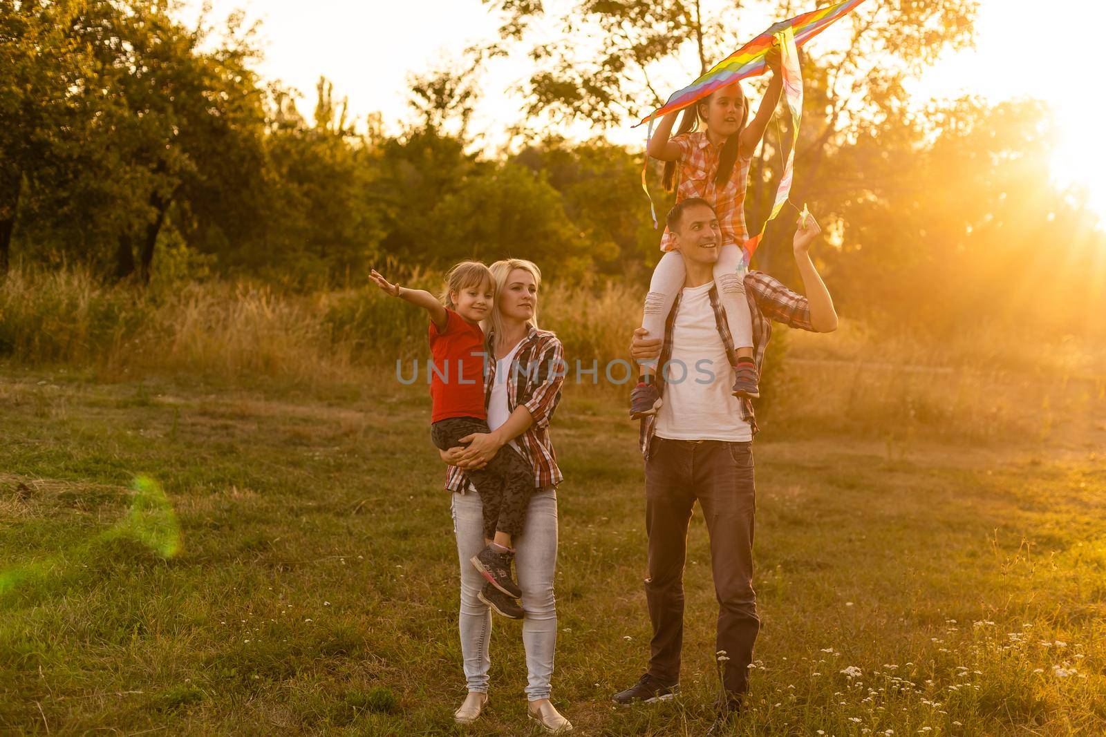 Happy family father of mother and daughters launch a kite on nature at sunset