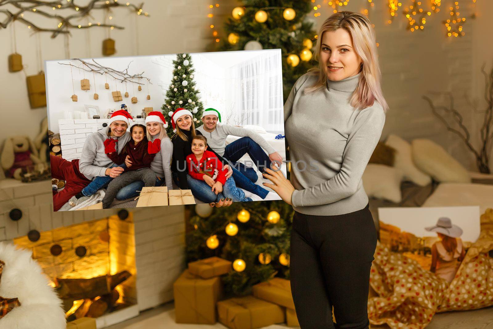 woman holding a photo canvas on the background of a Christmas interior.