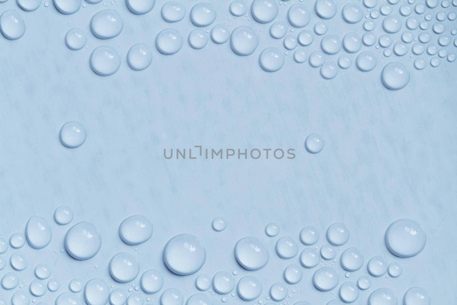 Big and small water drops on blue background. Closeup.