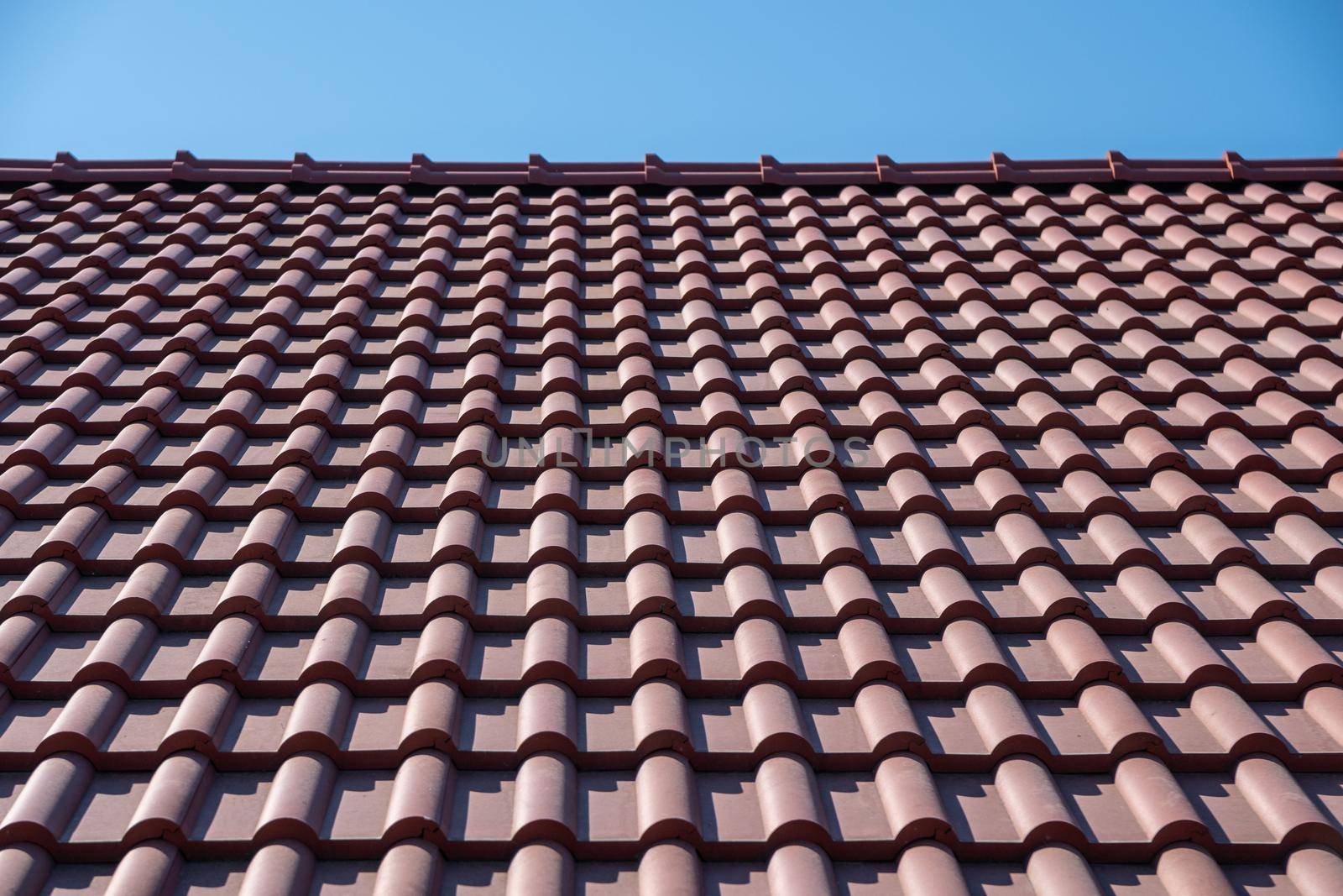 Brown tile roof under blue sky. The photo is divided on two part. One part is a roof made of clay tiles and the other is a pure blue sky. Place for text. by panophotograph