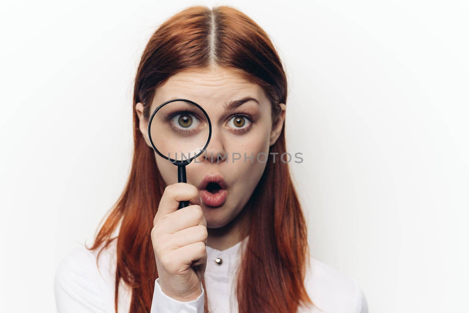 pretty woman grimacing with magnifying glass near face. High quality photo