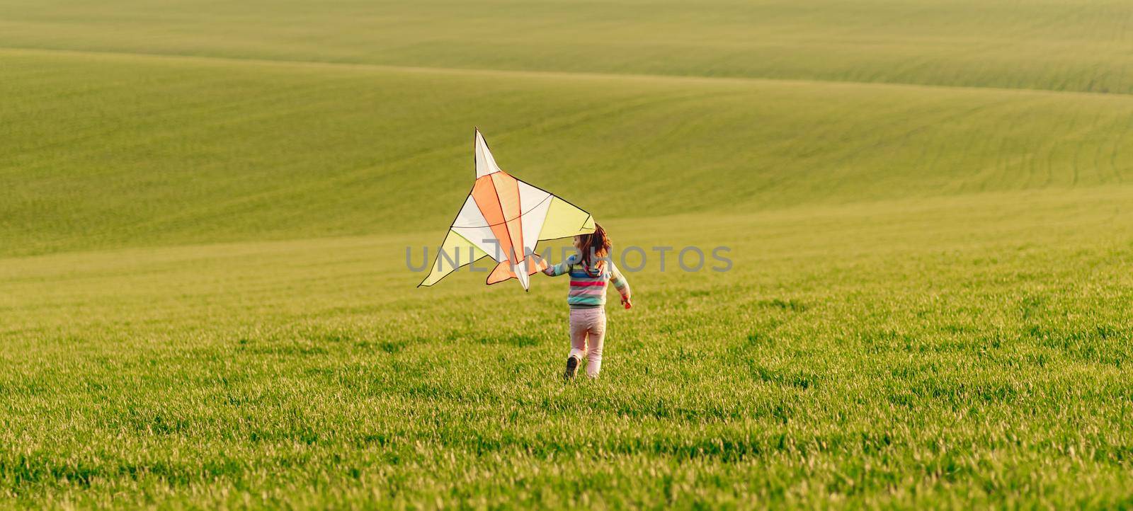 Little girl holding kite at sunset by tan4ikk1