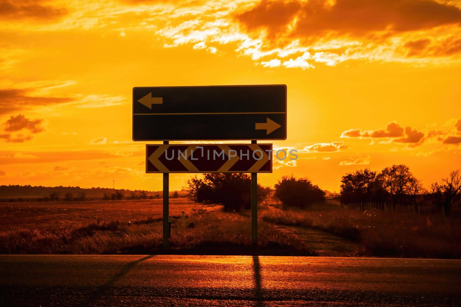 Empty blue direction crossroads road signs representing oportunities with red burning sunset background. Choose your strategy. Copyspace
