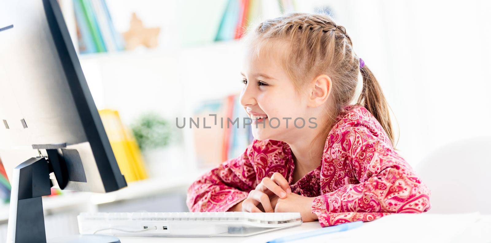 Happy little girl looking at computer screen by tan4ikk1