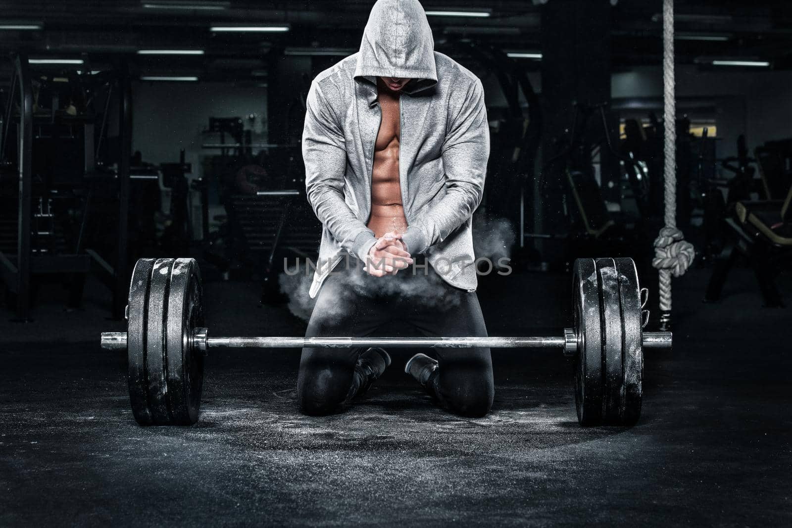 Athletic shirtless young sports man - fitness model with barbell in gym.