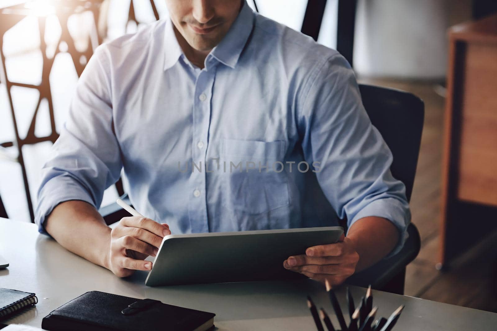 A male marketing manager using a pen point tablet to design a company's sales plan to present work to potential venture capitalists to maximize profits. by Manastrong
