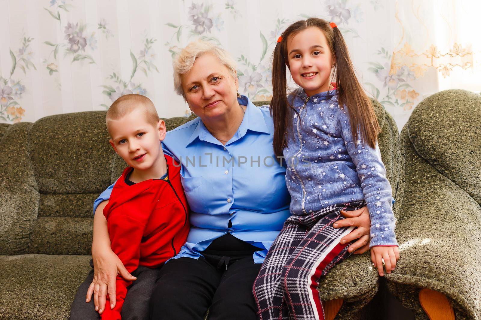 Grown up adult smiling grandchildren embraces elderly grandmother glad to see missing her, visit of loving relatives enjoy communication, cuddle as symbol of connection, love and support concept