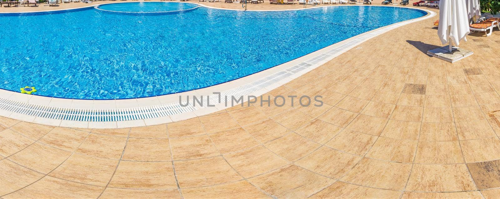 Pool with pure blue water background. Top view of swimming pool and floor texture. Panorama of pool bottom with tile pattern and transparent water. Summer travel and vacation background concept.